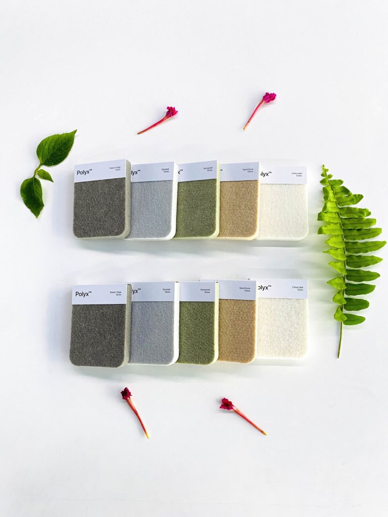 Two rows of fabric swatches in neutral shades are arranged on a white background, surrounded by green leaves and small red flowers—ideal for creating acoustically balanced retail spaces. Each swatch has a label at the top.