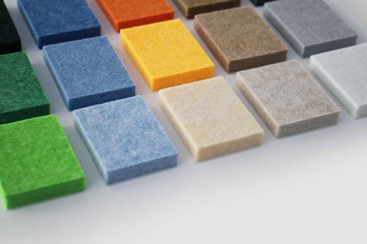 Rectangular fabric swatches in various colors are arranged in rows on a white surface, showcasing shades ideal for FSC Chain of Custody Wall Panels.