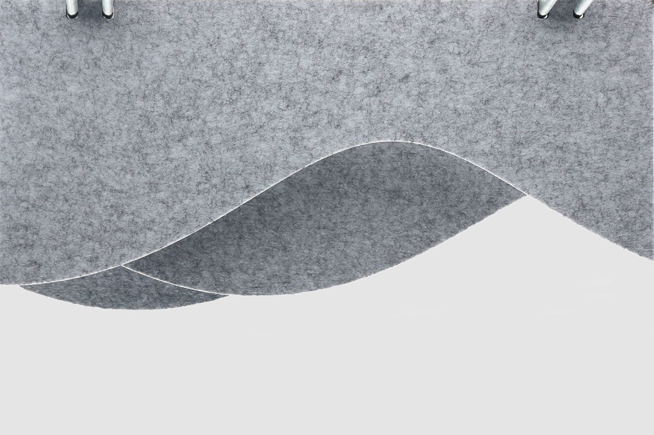 A close-up of overlapping, curved gray polyester acoustic panels offerings suspended from the ceiling against a plain background. The panels have a soft, felt-like texture and create a wave-like pattern.